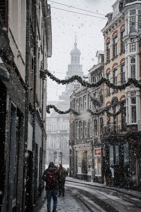 people walking near street between brown building during snow season