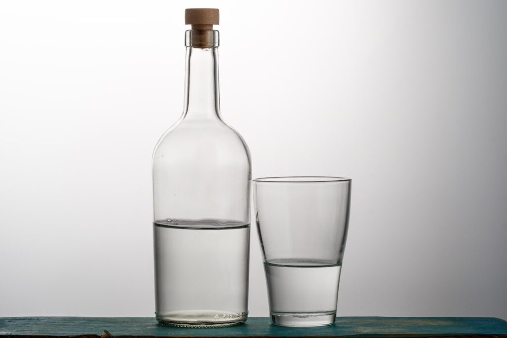 two clear drinking glasses beside bottle